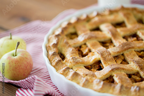 food, culinary and baking concept - apple pie and kitchen towel on wooden table