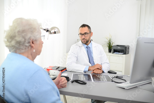 handsome doctor giving medical consultation diagnostic  to elderly senior woman in hospital office