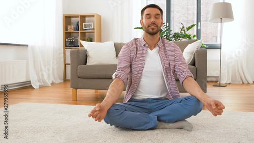 mindfulness, spirituality and relax concept - man meditating in lotus pose at home