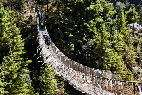 Trekkers on rope hanging suspension bridge on the way to Mount Everest base camp near Namche Bazar - Nepal