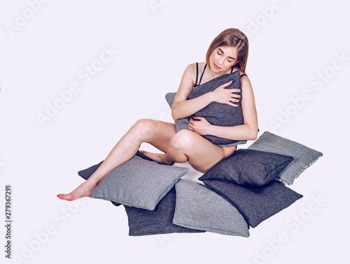 Relaxed girl hugging pillows while sitting on the floor. Sleep, relaxation, rest