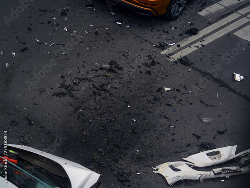 White modern car with a dent and broken bumper after an accident on an empty street surrounded by debris. The view from the window