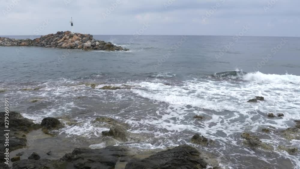 The Mediterranean Sea, waves breaking and lapping upon rocks at the harbor entrance of Sissi, Crete
