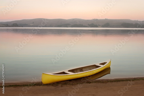 Yellow canoe on the shore of Tomales Bay at dusk with pastel colors and glassy water