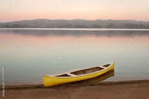 Yellow canoe on the shore of Tomales Bay at dusk with pastel colors and glassy water photo