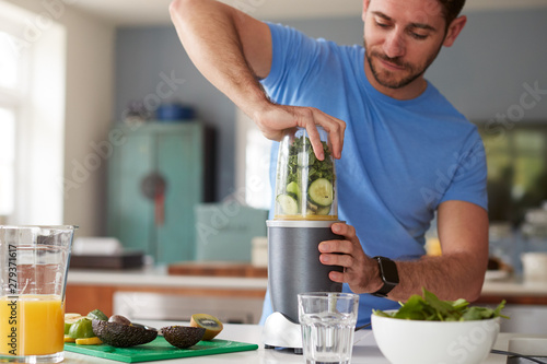 Man Making Healthy Juice Drink With Fresh Ingredients In Electric Juicer After Exercise photo