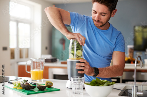 Man Making Healthy Juice Drink With Fresh Ingredients In Electric Juicer After Exercise