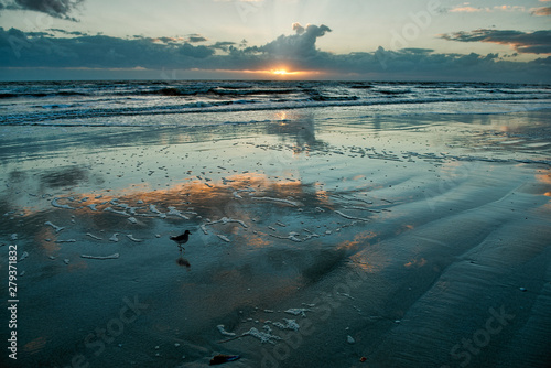Clouds reflected in wet sand at sunset
