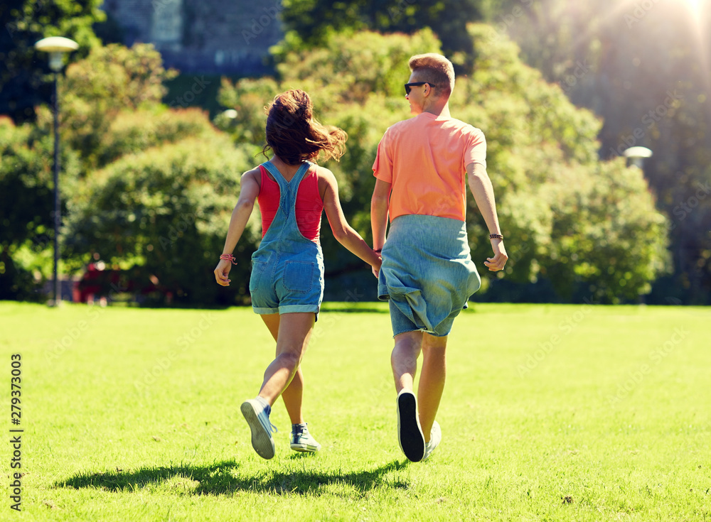love and people concept - happy teenage couple walking and looking at each other in summer park love and people concept - happy teenage couple walking and looking at each other in summer park