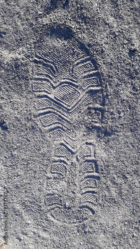 Footprint in gray clear sand closeup. Circle patterns of running shoe sole imprint on dry surface.
