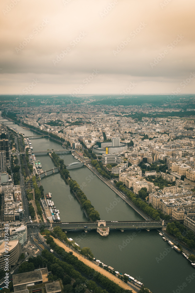 Vertical aerial moody view of Seine river and cityscape in Paris, France on a cloudy day