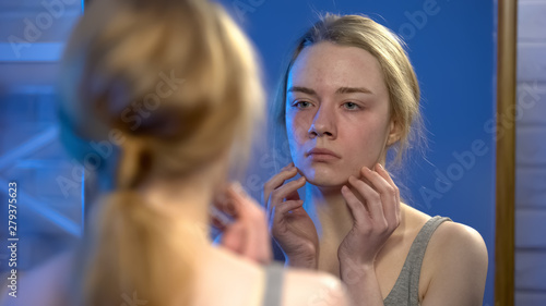 Canvas Print Unhappy young lady looking in mirror reflection, skin imperfection, insecurity