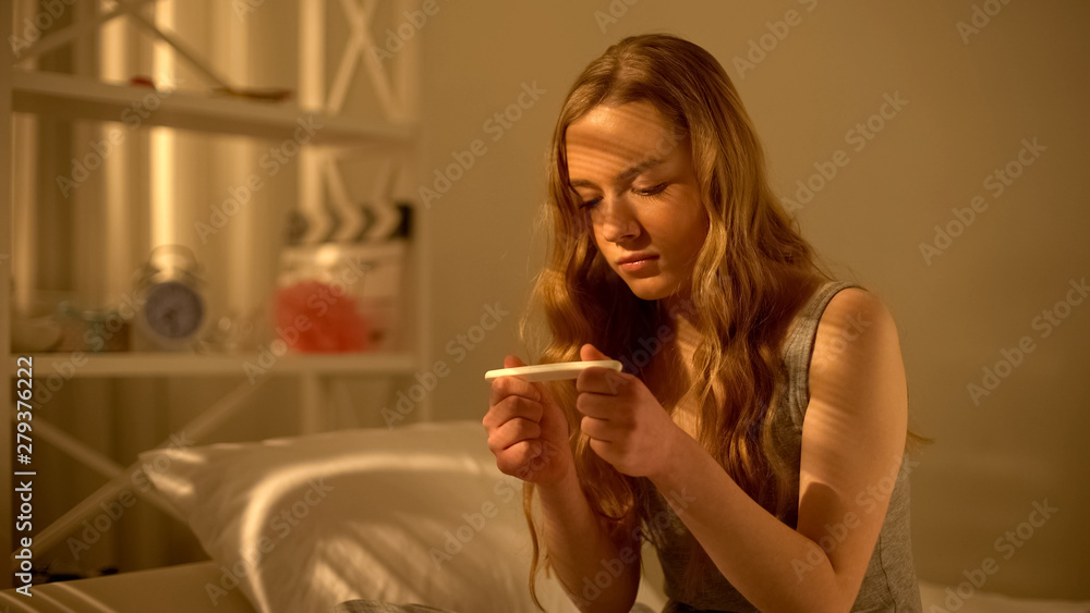 Young woman looking at pregnancy test result in contraception, unplanned child Young woman looking at pregnancy test result in contraception, unplanned child