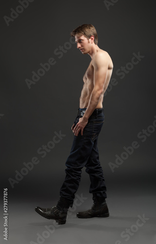 Full length portrait of a sexy young man in jeans and shirtless posing at studio. © Igor Borodin
