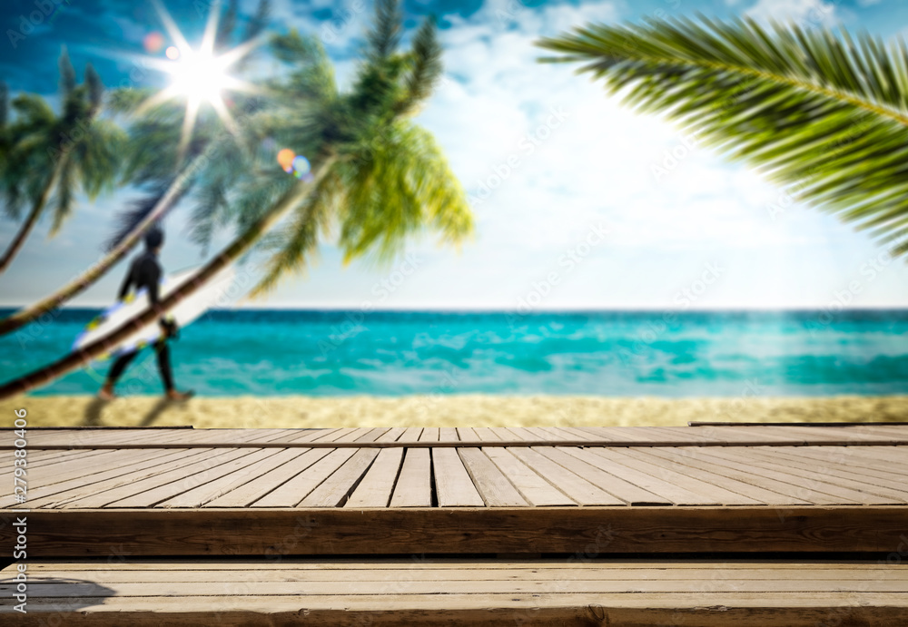 Wooden table top backround with beautiful calm ocean in distance. Some palm leaves above the wooden top board. Empty space for an advertising product.