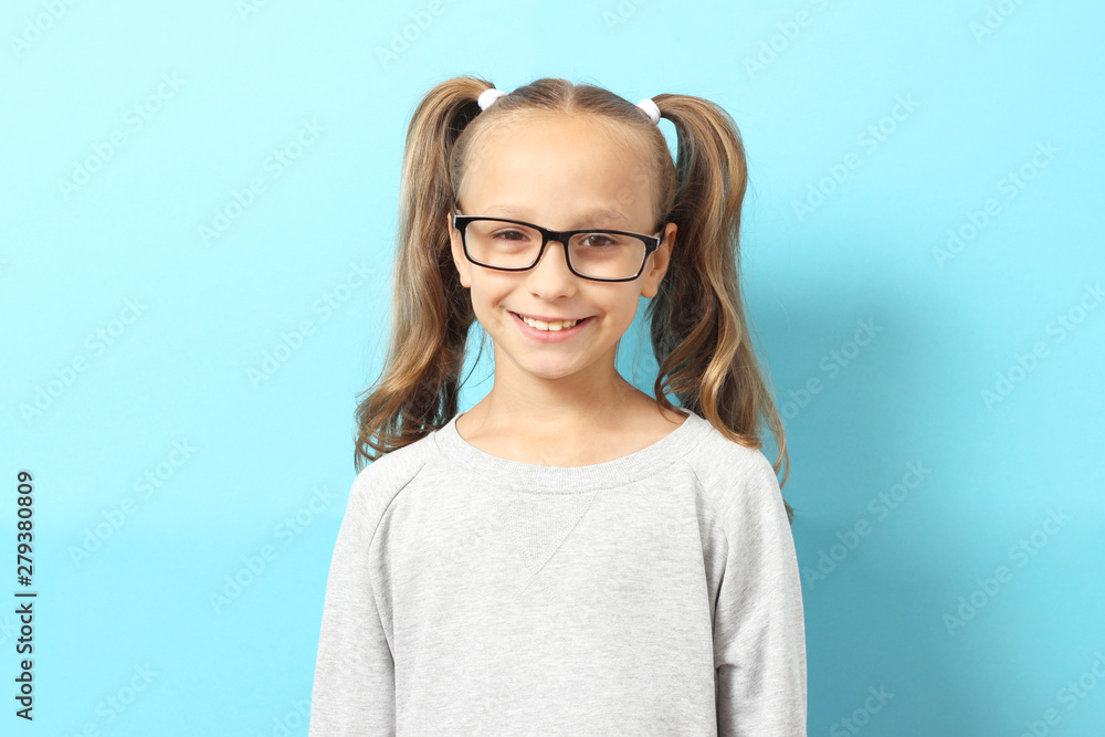 Portrait of a cute smiling girl in glasses on a color background.