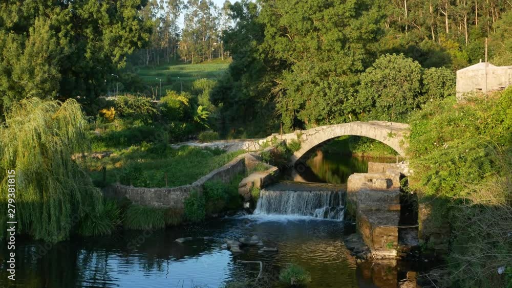 Old Roman bridge and waterfall over Este River in Vila do Conde, Portugal with overhanging weeping willow tree. Beautiful rural scene. Old Roman bridge and waterfall over Este River in Vila do Conde, Portugal with overhanging weeping willow tree. Beautiful rural scene.