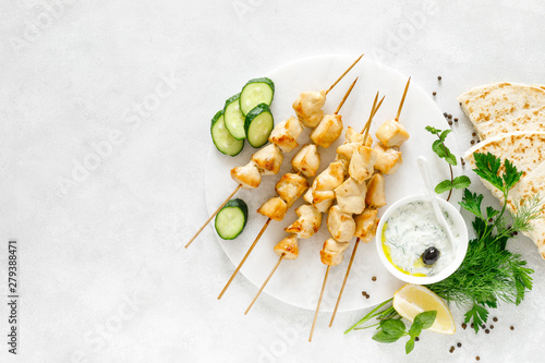 Grilled chicken kebab on skewers and traditional Greek tzatziki yogurt sauce, view from above