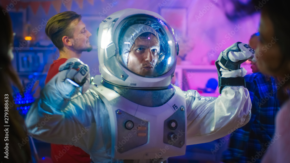 At the College House Costume Party: Fun Guy Wearing Space Suit Dances Off, Doing Robot Dance Modern Moves. With Him Beautiful Girls and Boys Dancing in Neon Lights. At the College House Costume Party: Fun Guy Wearing Space Suit Dances Off, Doing Robot Dance Modern Moves. With Him Beautiful Girls and Boys Dancing in Neon Lights.