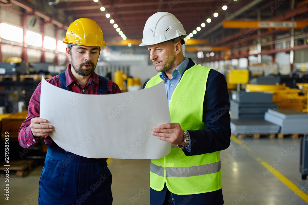 Engineers in hard hats working on a blueprint at the industrial plant. Engineers in hard hats working on a blueprint at the industrial plant.