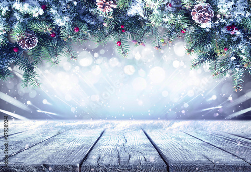 Festive Christmas stage scene background frame. Green fir branches covered with snow, decorated with cones and red berries and empty wooden flooring platform. Beautiful round bokeh, copy space.