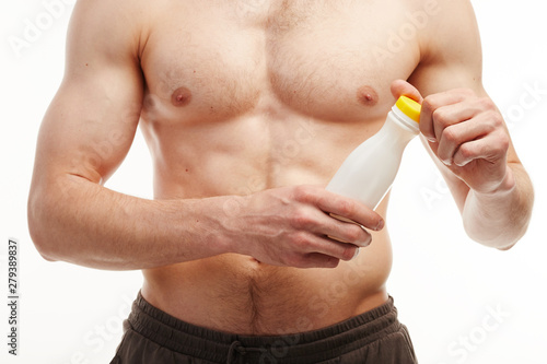 Close up of a man showing his six-pack while opening a bottle.