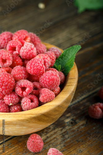 Fresh raspberries in a wooden bowl on a wooden table