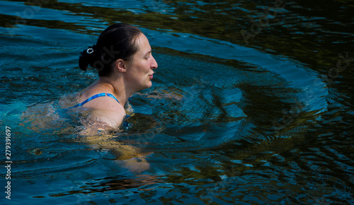 Woman swims in the river on a summer day.