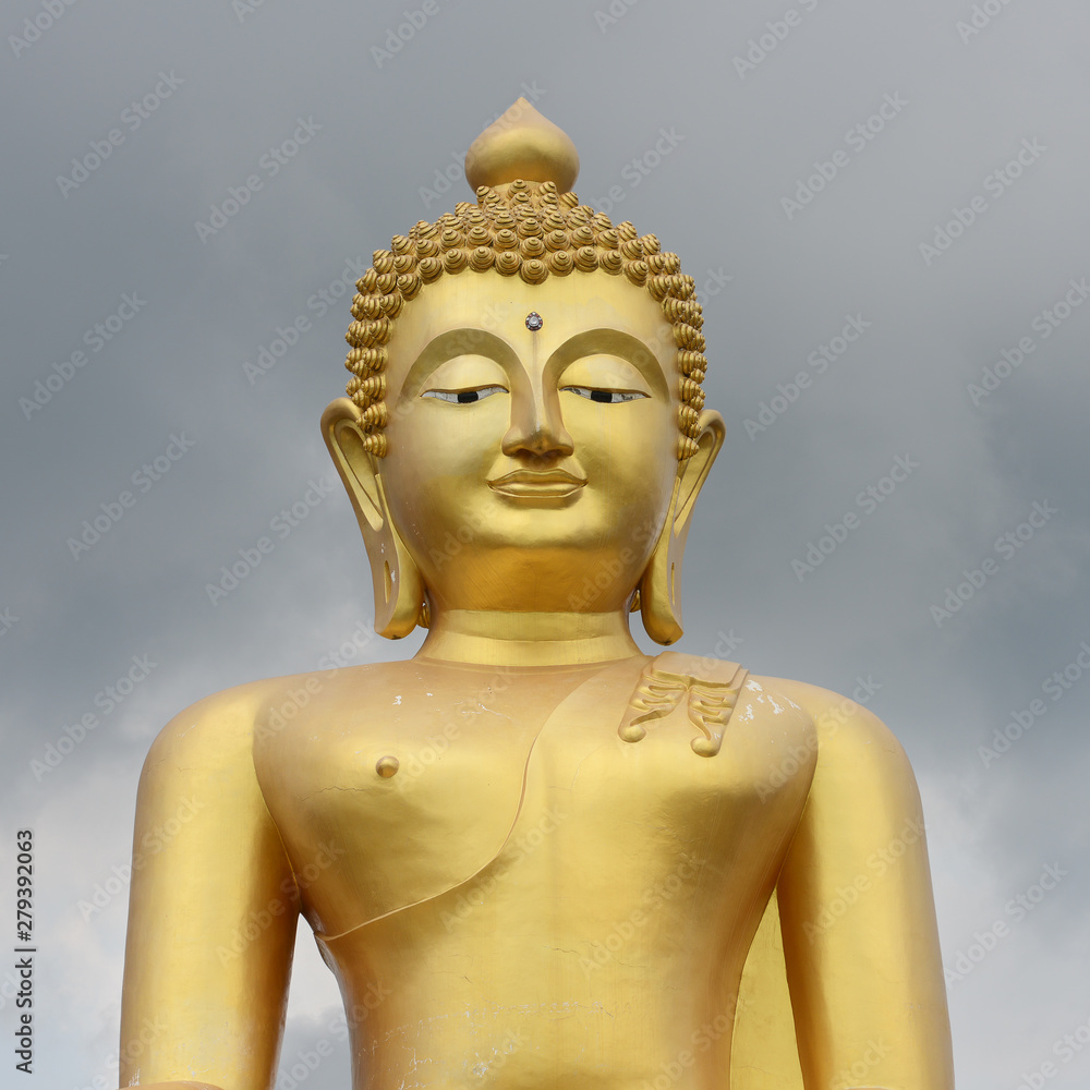 Big Golden Buddha statue on cloudy grey sky background. Koh Kood (Koh Koot) island, Thailand.