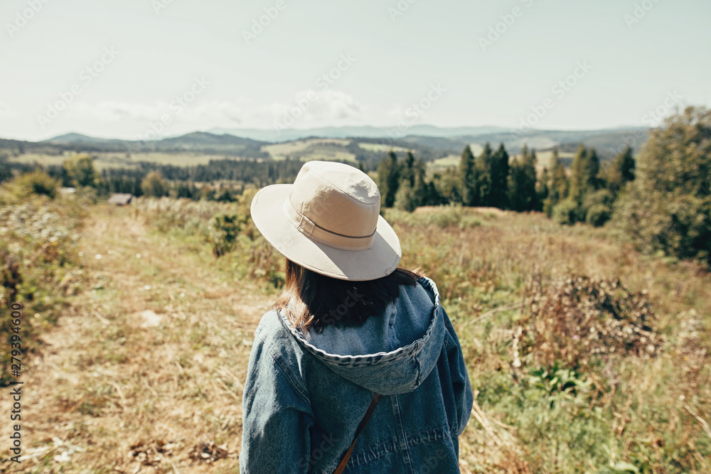 Stylish hipster girl travelling in sunny mountains. Woman in hat exploring and hiking on top of mountain on summer vacation. Wanderlust and travel concept Stylish hipster girl travelling in sunny mountains. Woman in hat exploring and hiking on top of mountain on summer vacation. Wanderlust and travel concept