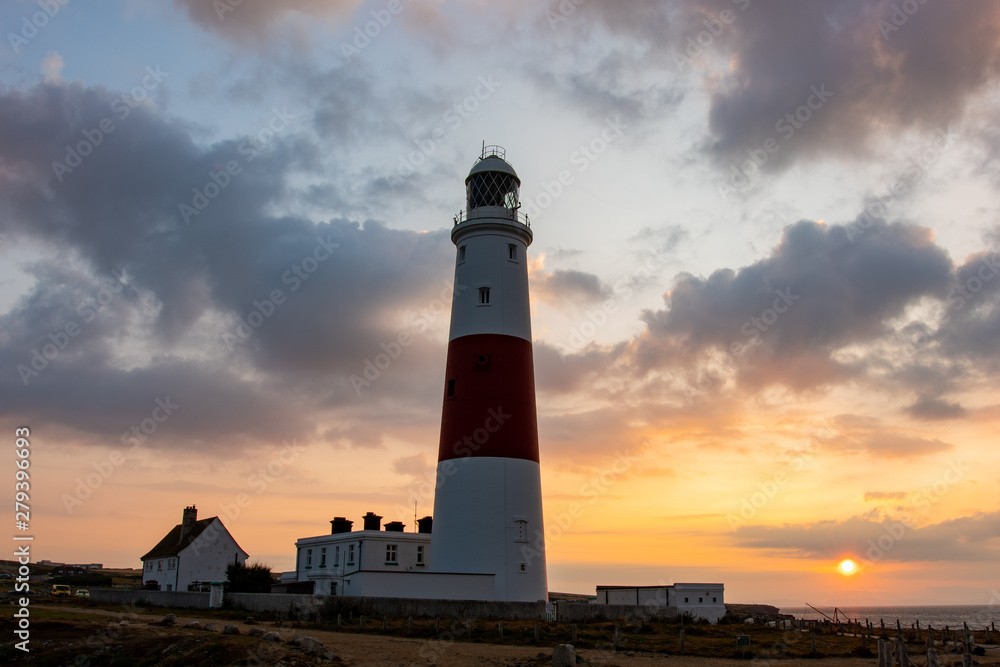 Portland Bill Lighthouse in Isle of Portland during sunrise with a sun coming up in the east