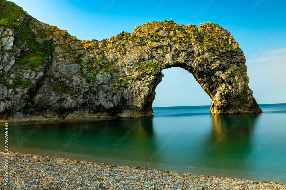 Durdle Door rock in Jurassic Coast in South England in a long exposure shot with nicely blurred calm water in the sea