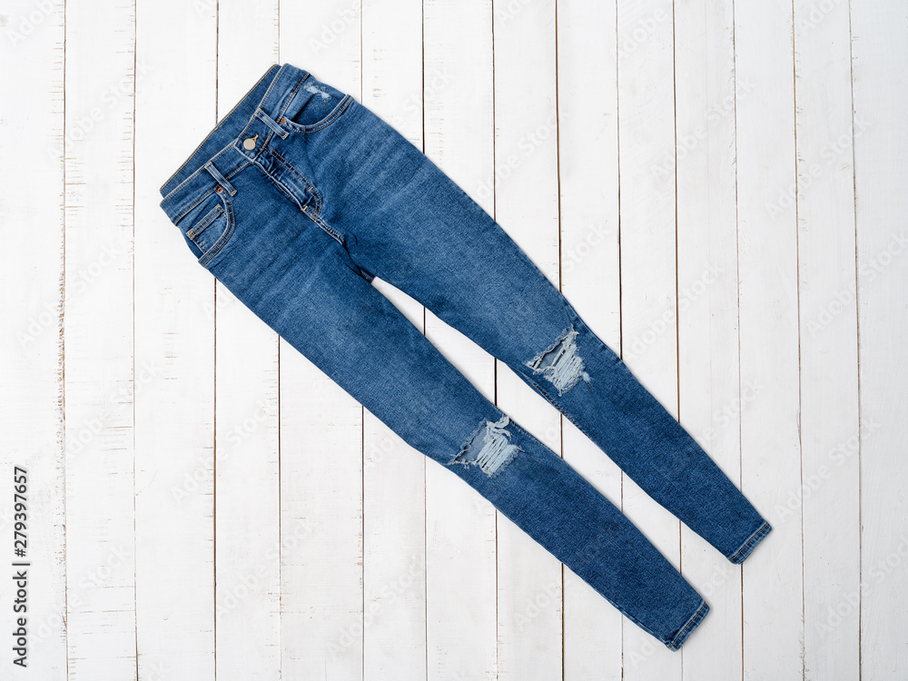 Blue ragged jeans on a white wooden background. Clothing concept. Flat lay  Stock Photo | Adobe Stock
