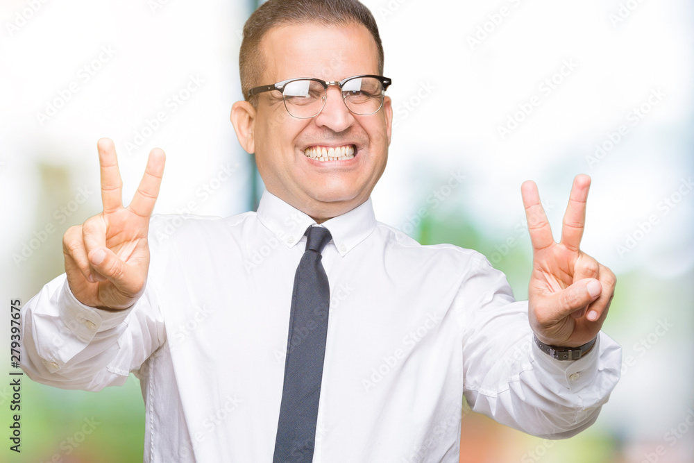 Middle age bussines arab man wearing glasses over isolated background smiling looking to the camera showing fingers doing victory sign. Number two. Middle age bussines arab man wearing glasses over isolated background smiling looking to the camera showing fingers doing victory sign. Number two.