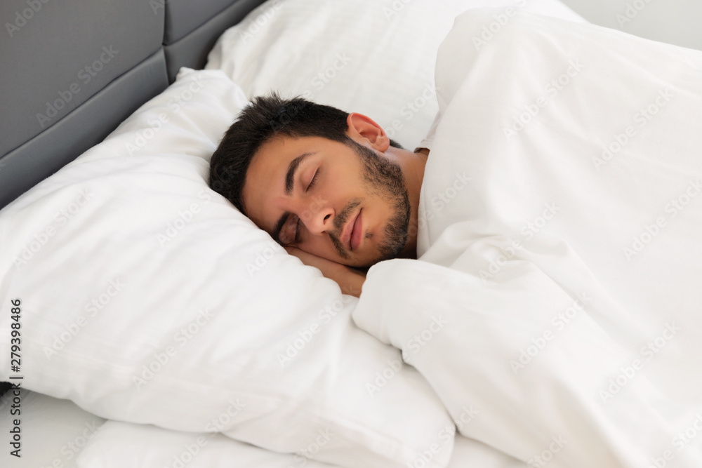 Young handsome man sleeping in his bed.