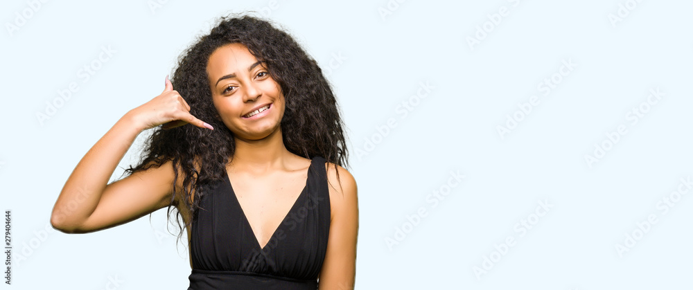Fototapeta premium Young beautiful girl with curly hair wearing fashion skirt smiling doing phone gesture with hand and fingers like talking on the telephone. Communicating concepts.