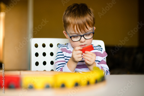 little ginger boy with glasses with syndrome dawn playing photo