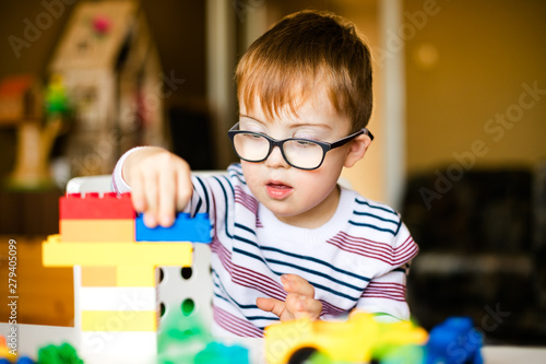 little ginger boy with glasses with syndrome dawn playing photo