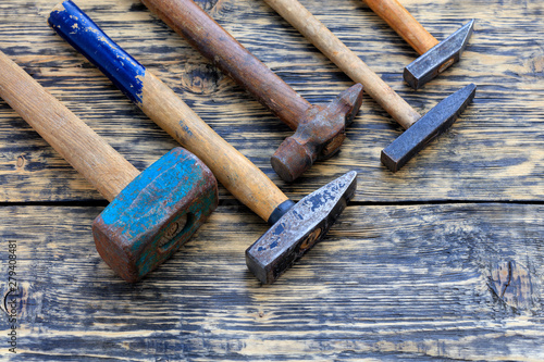 Old iron hammers lie on a wooden table.