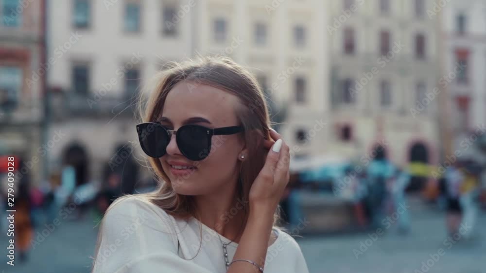 Seductive hot young blonde woman walking down the crowded city center, lowers her trendy sunglasses and excitedly looks around. Trendy outfit, stylish, fashion and vogue concept Seductive hot young blonde woman walking down the crowded city center, lowers her trendy sunglasses and excitedly looks around. Trendy outfit, stylish, fashion and vogue concept