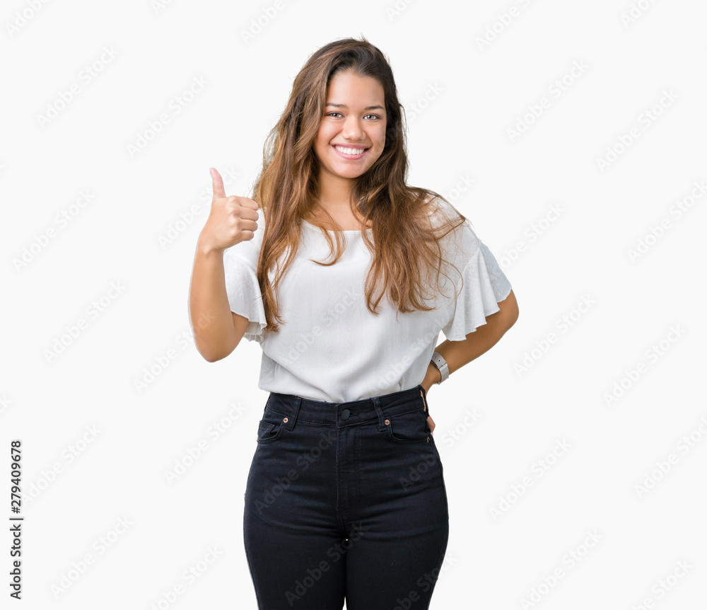 Young beautiful brunette business woman over isolated background doing happy thumbs up gesture with hand. Approving expression looking at the camera showing success. Young beautiful brunette business woman over isolated background doing happy thumbs up gesture with hand. Approving expression looking at the camera showing success.