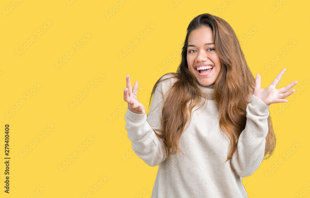 Young beautiful brunette woman wearing turtleneck sweater over isolated background celebrating crazy and amazed for success with arms raised and open eyes screaming excited. Winner concept Young beautiful brunette woman wearing turtleneck sweater over isolated background celebrating crazy and amazed for success with arms raised and open eyes screaming excited. Winner concept