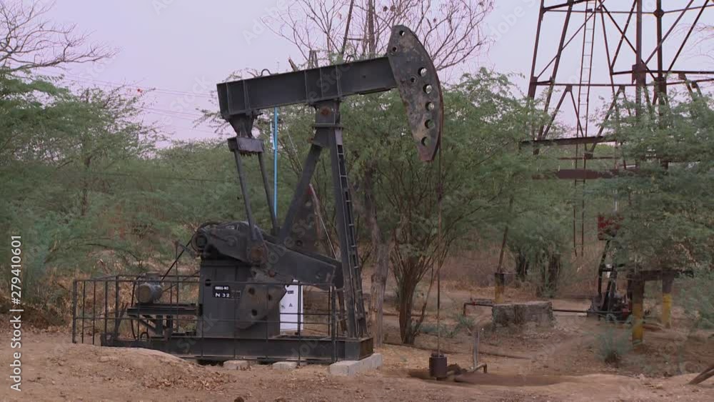 A steady, medium shot of a small pump extracting the oil at a petroleum station, in the middle of nowhere. A steady, medium shot of a small pump extracting the oil at a petroleum station, in the middle of nowhere.