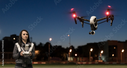 The girl controls the quadcopter. Drone in the night sky. The operator of the copter. The night sky and the lights. Flights on the quadrocopter.