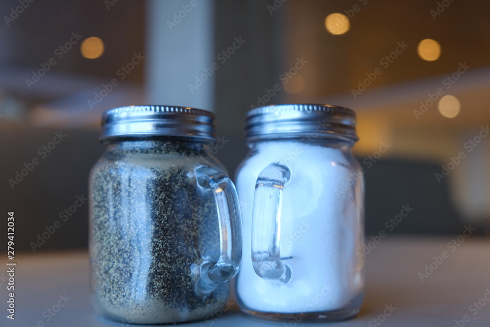Contenitore per sale e pepe trasparente sul tavolo con luci posteriori e sfuocato Contenitore per sale e pepe trasparente sul tavolo con luci posteriori e sfuocato