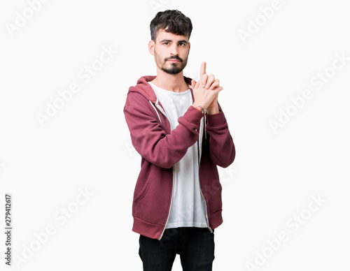 Young handsome man over isolated background Holding symbolic gun with hand gesture, playing killing shooting weapons, angry face