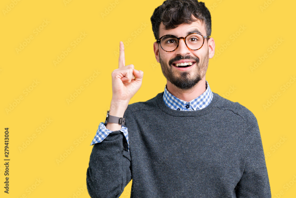 Young handsome smart man wearing glasses over isolated background pointing finger up with successful idea. Exited and happy. Number one. Young handsome smart man wearing glasses over isolated background pointing finger up with successful idea. Exited and happy. Number one.