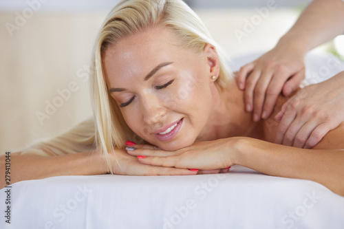 Beautiful young woman relaxing during full body massage at spa