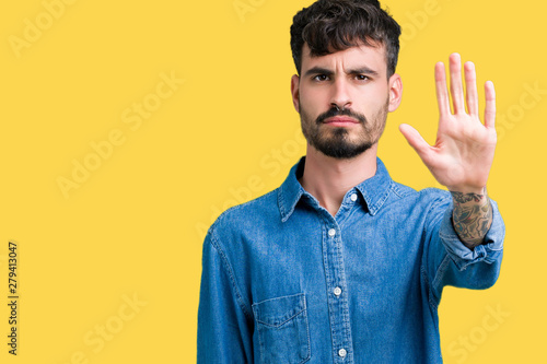 Young handsome man over isolated background doing stop sing with palm of the hand. Warning expression with negative and serious gesture on the face. © Krakenimages.com