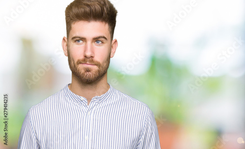 Young handsome man smiling looking side and staring away thinking.